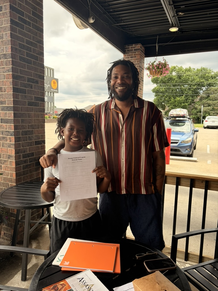 Student holding Dreams Preferred welcome packet with mentor
